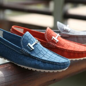 Fashionable leather loafers in various colors displayed on a wooden railing outdoors.